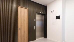 A hallway with a wooden door, a vertical striped wall, and a closed elevator. - Opera 503 in Medell n (Medellín)
