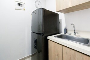 A kitchen with a black refrigerator, a sink, wooden cabinets, and a wall clock. - Oslo 604a in Medell n (Medellín)