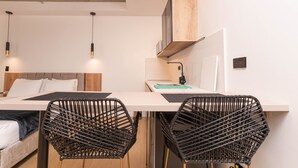 A modern room with a bed, a desk, two black chairs, a flat-screen TV, and a wooden shelf. - Opera 201 in Medell n (Medellín)