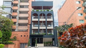 A multi-story building with a modern design, featuring balconies with plants, a central entrance, and a brick facade. - Opera 201 in Medell n (Medellín)