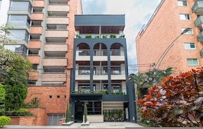A multi-story building with a modern design, featuring balconies with plants, a central entrance, and a brick facade. - Opera 201 in Medell n (Medellín)