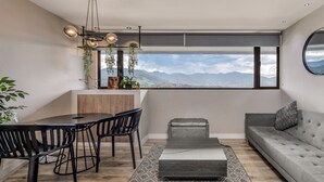 A modern living space with a dining area, a sofa, and a view of mountains. - Go Living Suites - 801 (Medellín)