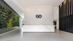 A modern reception area with a logo, a green wall, and a marble counter. - Go Living Suites - 801 (Medellín)