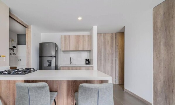 Une cuisine moderne dotée d’un îlot central, d’une cuisinière encastrée et d’un réfrigérateur.