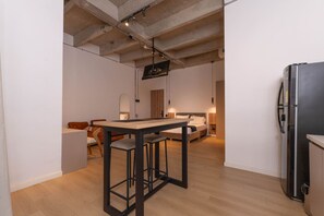 Une cuisine moderne avec un coin repas, un réfrigérateur et un lit à l’arrière-plan.