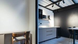 Una cocina moderna con armarios blancos, microondas integrado y cafetera.
