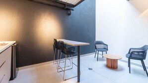 Una cocina moderna con encimera blanca, sillas negras y una mesa de madera.
