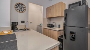 A modern kitchen with a built-in gas stove, a refrigerator, wooden cabinets, a microwave, and a wall clock. - Oslo 603 B in Medell n (Medellín)
