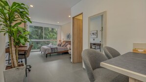 A modern room with a bed, desk, and dining area, featuring large windows and a potted plant. - Oslo 603 B in Medell n (Medellín)