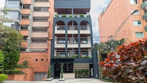 A multi-story building with a brick facade, balconies with plants, and a central entrance with a canopy. - Opera 301 in Medell n (Medellín)