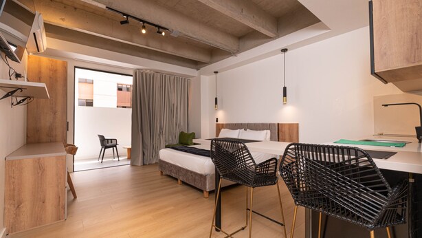 A modern hotel room with a bed, two black wireframe chairs, a desk, and a large window. - Opera 301 in Medell n (Medellín)