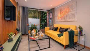 A modern living room with a yellow sofa, glass coffee table, and a neon sign on the wall. - Ayamonte - 301b in Medell n (Medellín)