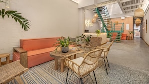 A cozy interior with a wooden table, wicker chairs, a sofa, and a staircase. - Botánica Básica (Medellín)