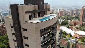 Ein Hochhaus mit Dachpool, mehreren Balkonen und Stadtblick im Hintergrund.
