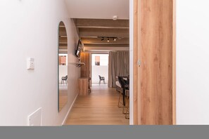 Ein modernes Interieur mit Holzboden, einer Essecke mit Tisch und Stühlen sowie einem großen Spiegel an der Wand.