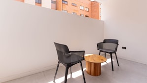 A modern interior with two black chairs and a wooden table, a white wall, and a view of a brick building. - Opera 501 in Medell n (Medellín)