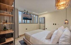 Un dormitorio moderno con una cama grande, un televisor montado en la pared y vistas de la ciudad.