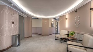 En modern inredning med ett välvt tak, en sittgrupp med en växt och vägvisningsskyltar på väggarna.