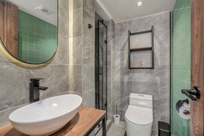 A modern bathroom with a large oval sink, a toilet, a shower enclosure, and a mirror. - Nutibara Express - 821 (Medellín)