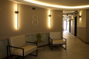 A hallway with two chairs, a potted plant, and a wall with a number '8' and 'PISO LEVEL' sign. - Nutibara Express - 821 (Medellín)