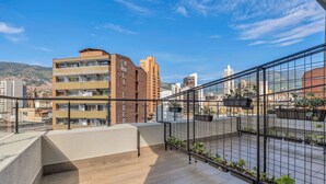 A rooftop terrace with a view of city buildings and mountains. - Nutibara Express - 825 (Medellín)