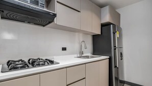 A modern kitchen with a gas stove, stainless steel refrigerator, and beige cabinetry. - Housy Laureles - 202 (Medellín)