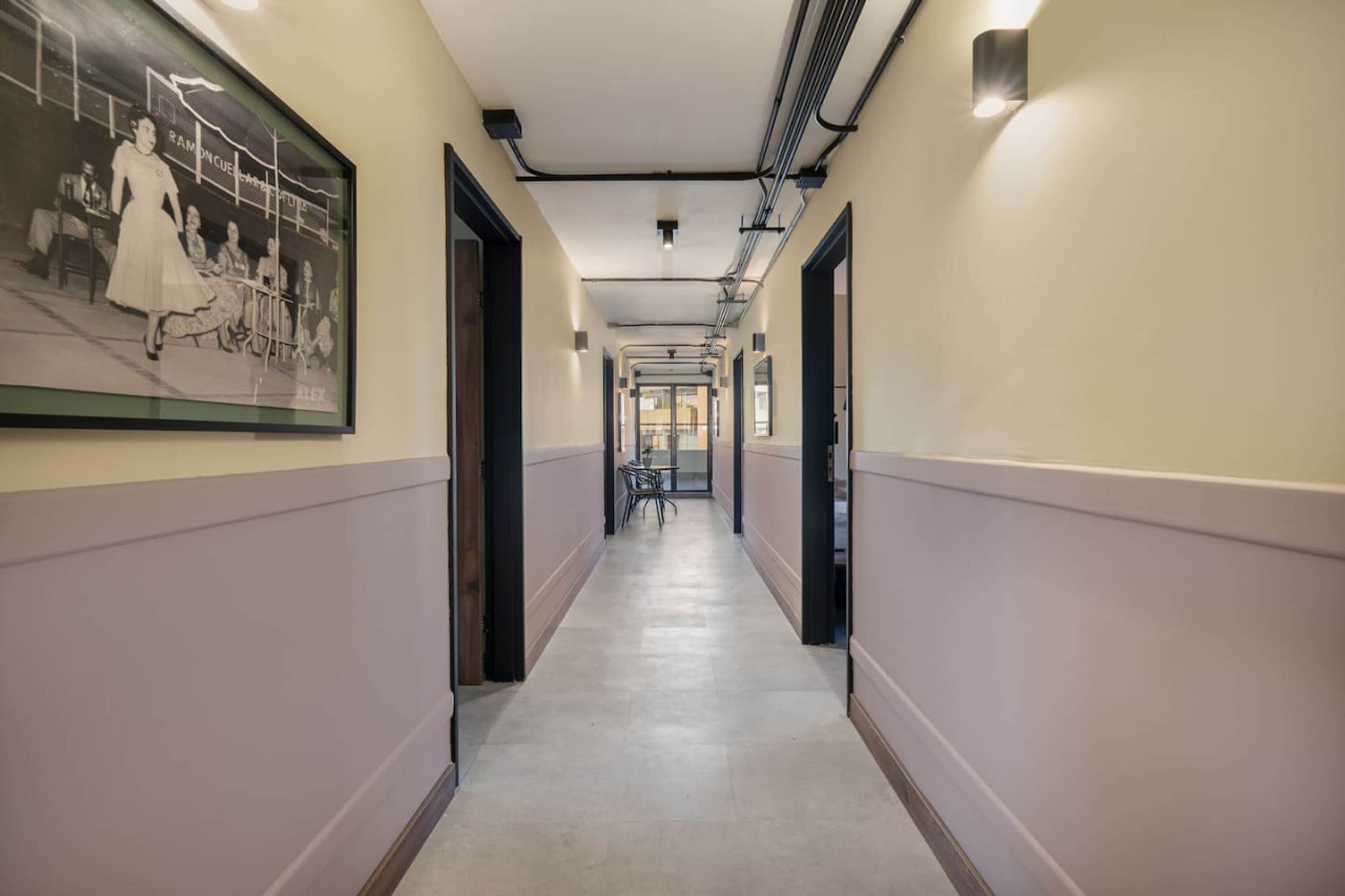 A hallway with a framed historical photo, doors on both sides, and a tiled floor.