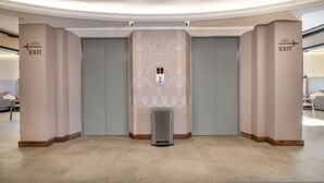 A modern elevator with a decorative wall design, two exit signs, and a control panel. - Nutibara Express - 827 (Medellín)