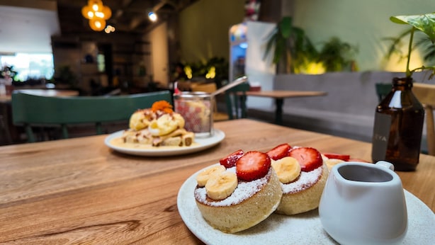 A dining table with two plates of desserts, a small pitcher, and a bottle. - Housy Laureles - 401 (Medellín)