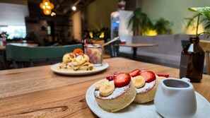 A dining table with two plates of desserts, a small pitcher, and a bottle. - Housy Laureles - 401 (Medellín)