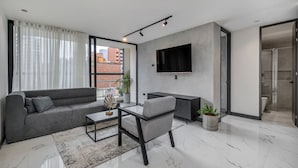 A modern living room with a sofa, a coffee table, a TV, and a small table with chairs. - Housy Laureles - 401 (Medellín)