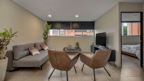 Una sala moderna con un sofá, dos sillones, un televisor y una cama.