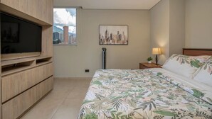 Ein Schlafzimmer mit einem Bett, einem Fernseher, einem Stadtbild und einem Fenster.