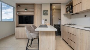 Eine moderne Küche mit Holzausstattung, einer eingebauten Mikrowelle und einem Barhocker.