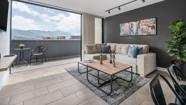 Een moderne woonkamer met een bank, salontafel en een groot raam met uitzicht op de stad.