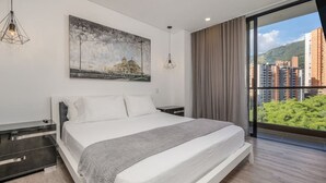 Ein modernes Schlafzimmer mit einem großen Bett, einem Gemälde und Blick auf Gebäude durch ein Fenster.
