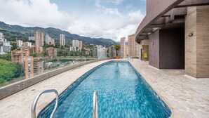 Ein Swimmingpool mit Blick auf eine Stadtlandschaft und dahinter Berge.