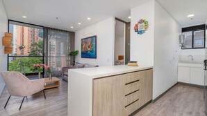 Ein modernes Hotelzimmer mit großem Fenster, Schreibtisch, Sofa und einem Gemälde an der Wand.