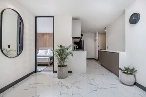 A modern hotel interior with a marble floor, a bed, a kitchen area, and a large mirror. - Housy Laureles - 402 (Medellín)