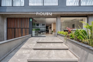 A modern building entrance with a glass door, a name sign, and a concrete staircase leading inside. - Housy Laureles - 402 (Medellín)