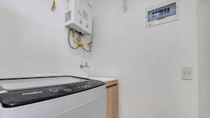 Une buanderie équipée d’un lave-linge Mabe, d’un chauffe-eau Bosch et d’un meuble en bois.