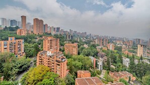 Un paysage urbain avec de hauts immeubles, une végétation luxuriante et un ciel nuageux.