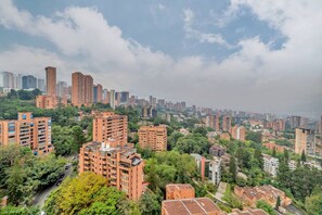 A cityscape with high-rise buildings, dense greenery, and a cloudy sky. - Oslo 2403 in Medell n (Medellín)