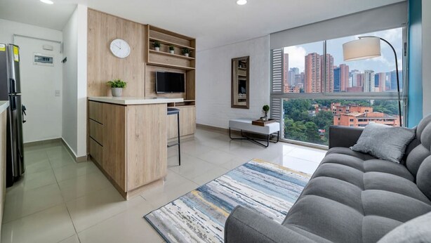 Un appartement moderne doté d’une cuisine, d’un coin repas et d’une grande fenêtre offrant une vue sur la ville.