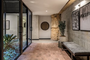 Eine moderne Lobby mit einer Bank, einem Glastür-Eingang, einer Steinwand und abstrakter Kunst.
