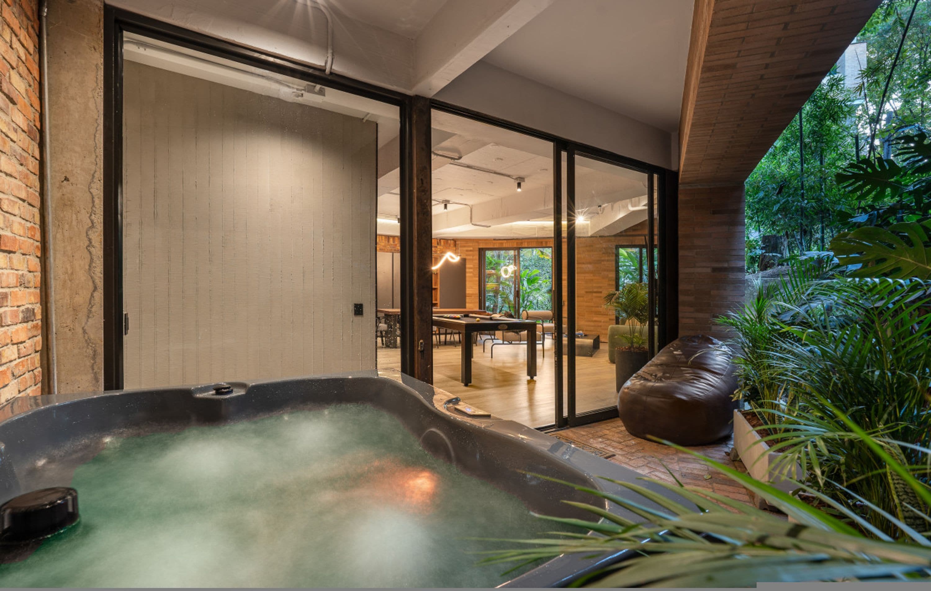A hot tub in a modern room with a sliding glass door leading to a dining area.
