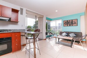 A modern kitchen with a dining area, a sofa, and a large window. - Cyan 803 - 2BR in Medell n (Medellín)