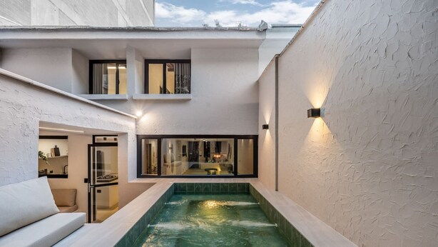A modern indoor pool area with a glass enclosure, a sofa, and a staircase leading to an upper level. - Luxurious 5BR House in Provenza Perfect for Groups (Medellín)