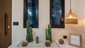 A room with a white console table, cacti, a wicker pendant light, and framed certificates. - Luxurious 5BR House in Provenza Perfect for Groups (Medellín)