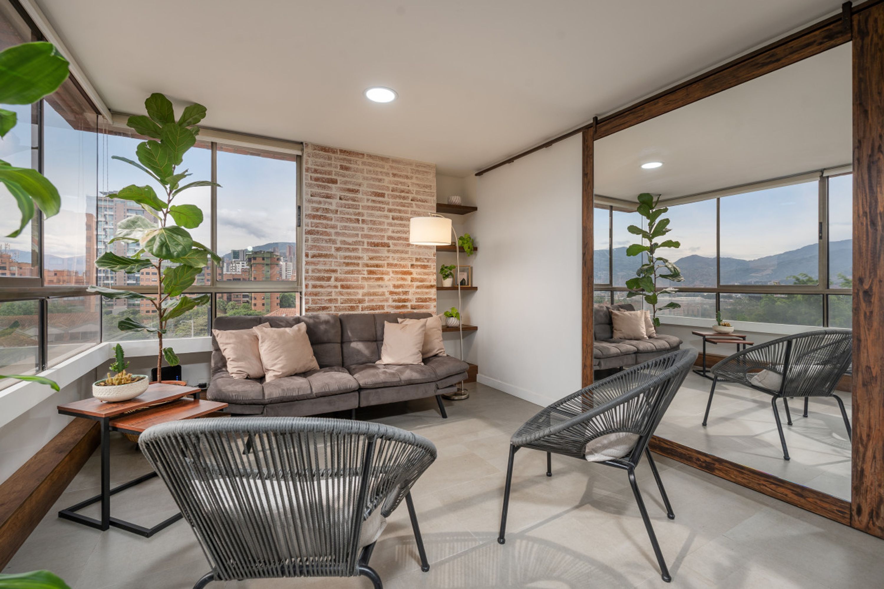 A modern living room with a brick accent wall, large windows, and a view of the city.